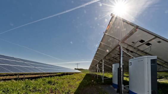 Ground-mounted PV plant with clear sky and sun in the background